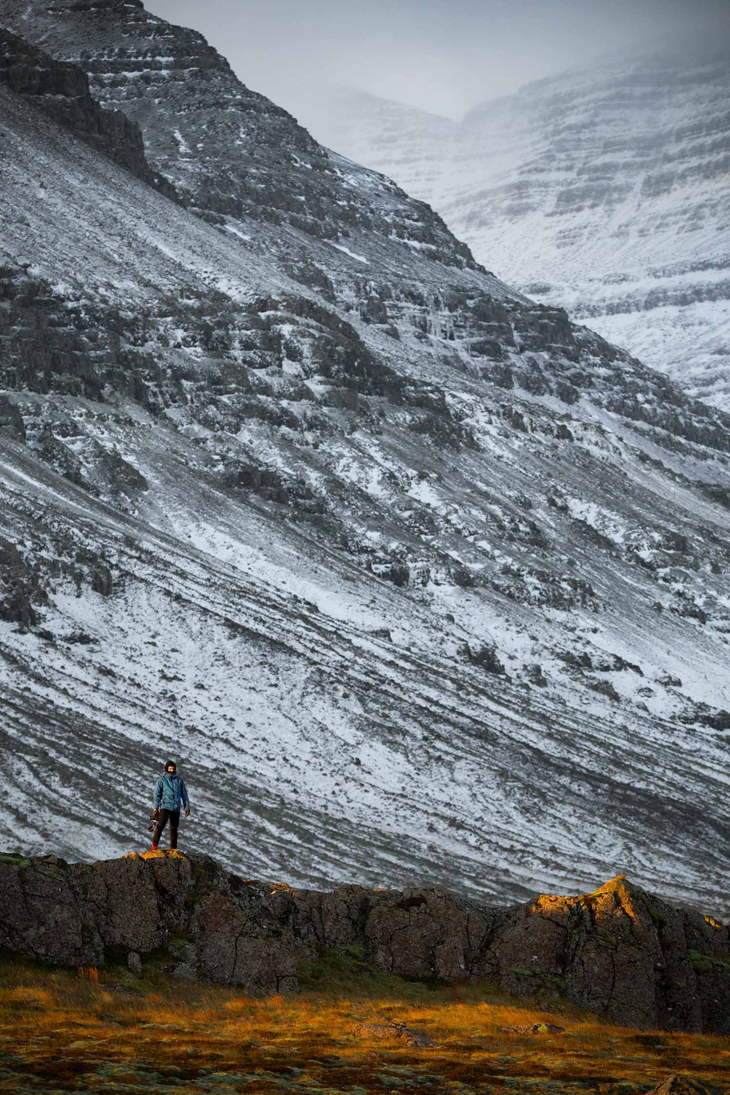 a person standing on a rock in front of a mountain